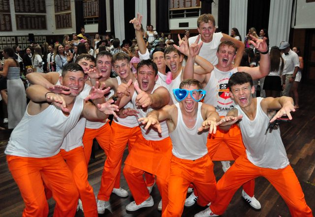 A team in matching orange outfits posing at a Musiekpret show